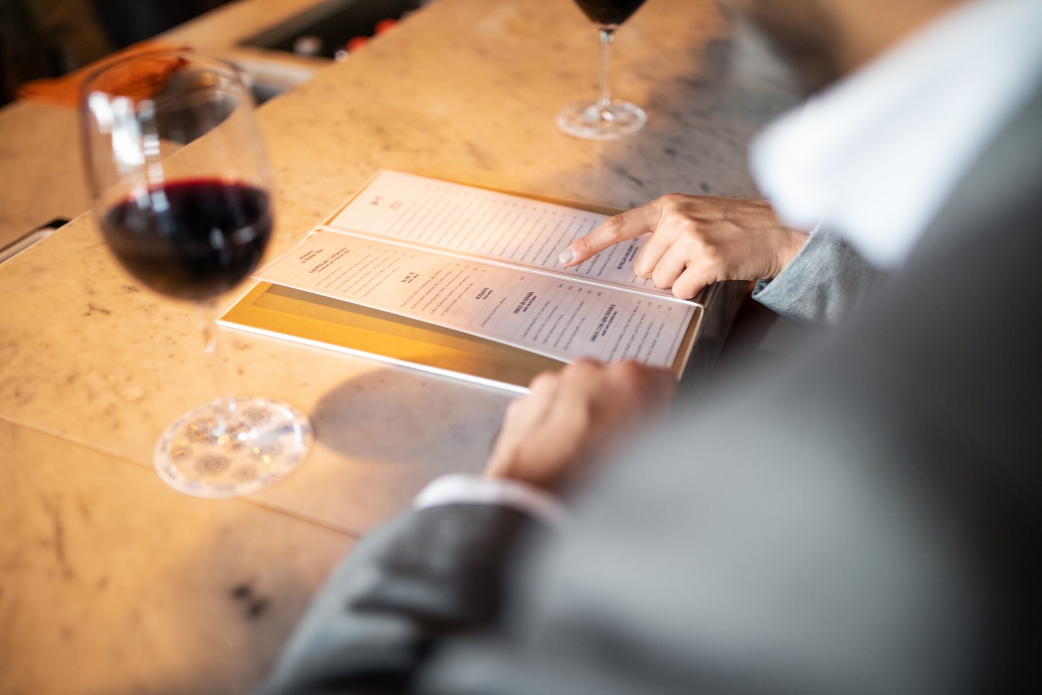 Close-up of two business colleagues sitting at a bar counter and looking at menu card. Couple discussing menu with male partner.