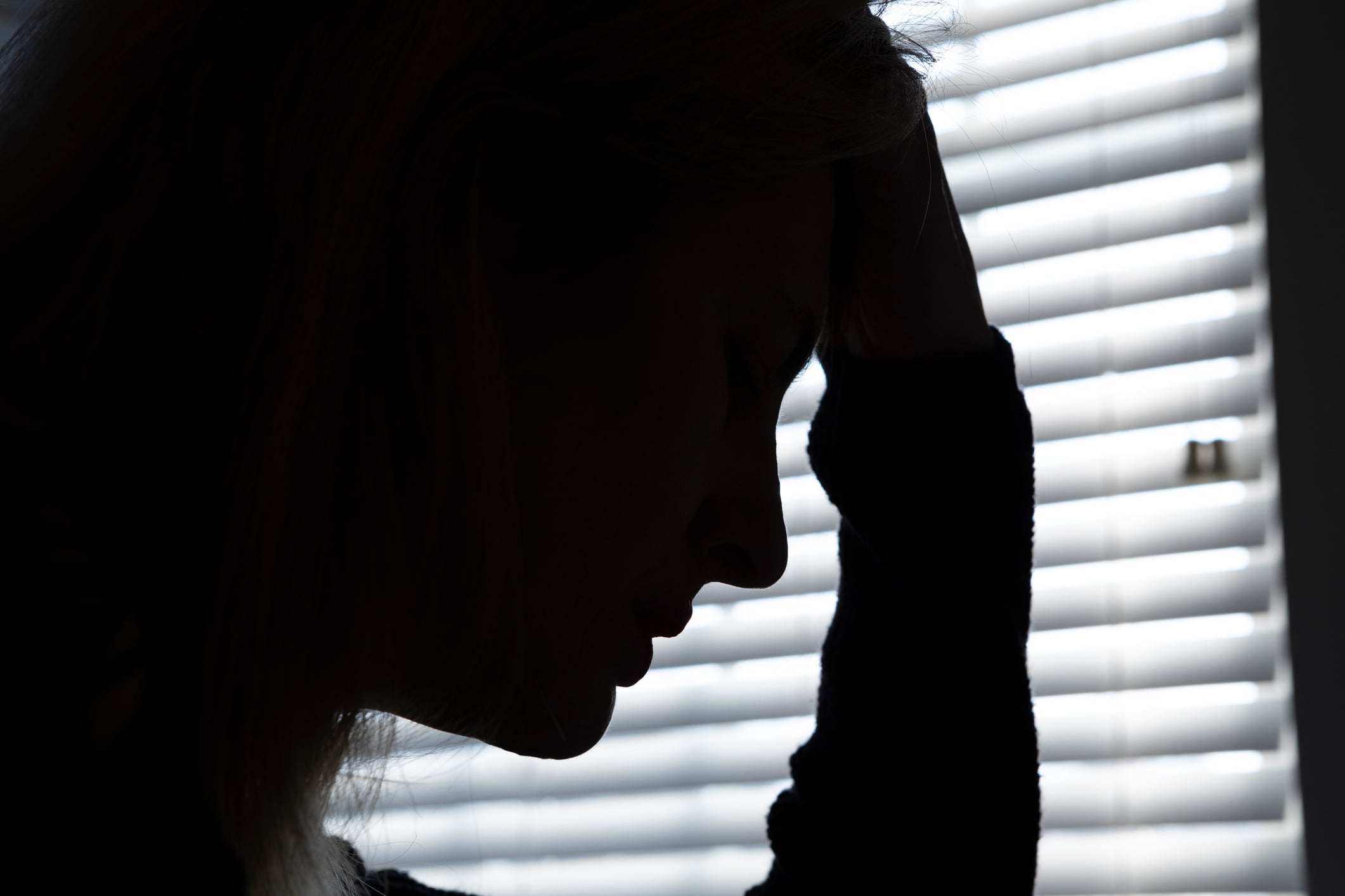 A woman sits with her head in her hands, conveying stress and despair -symbolising the emotional toll of widespread job losses in the hospitality sector.