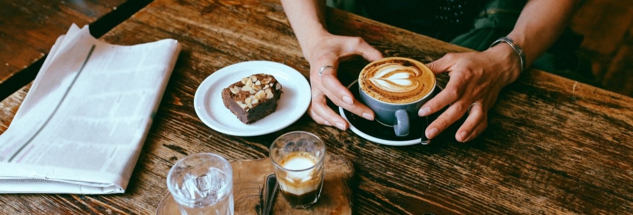 Latte art coffee in a cup with a brownie on a plate