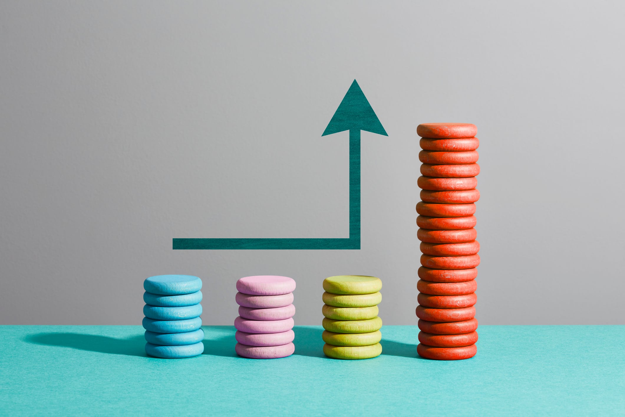 Arrow above four stacks of coloured coins signalling business growth in pub groups.