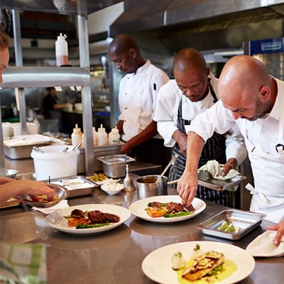 different-chefs-finishing-food-in-kitchen.jpg