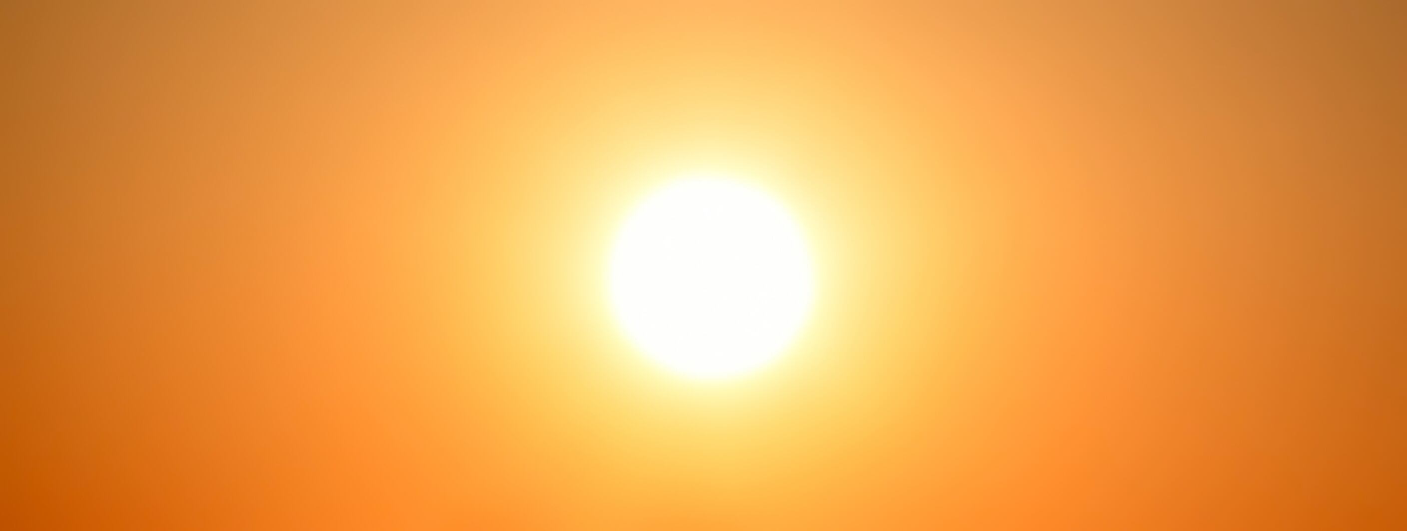 Strong sunlight shining in the orange golden yellow sky. Heat wave in the summer.