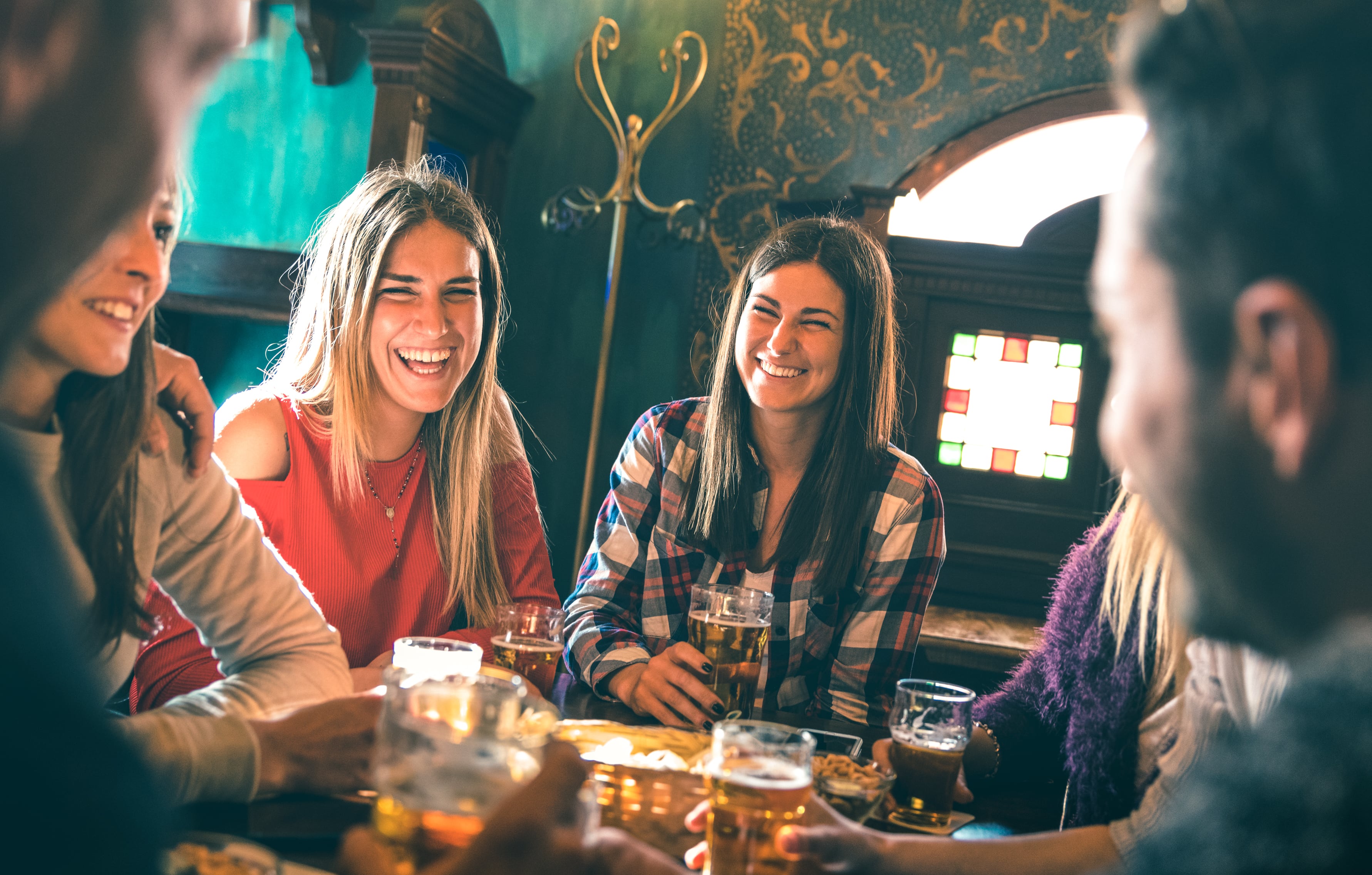 Group of happy friends drinking beer at brewery bar restaurant - Friendship concept with young millenial people enjoying time together having fun vintage pub - Focus right woman - High iso image