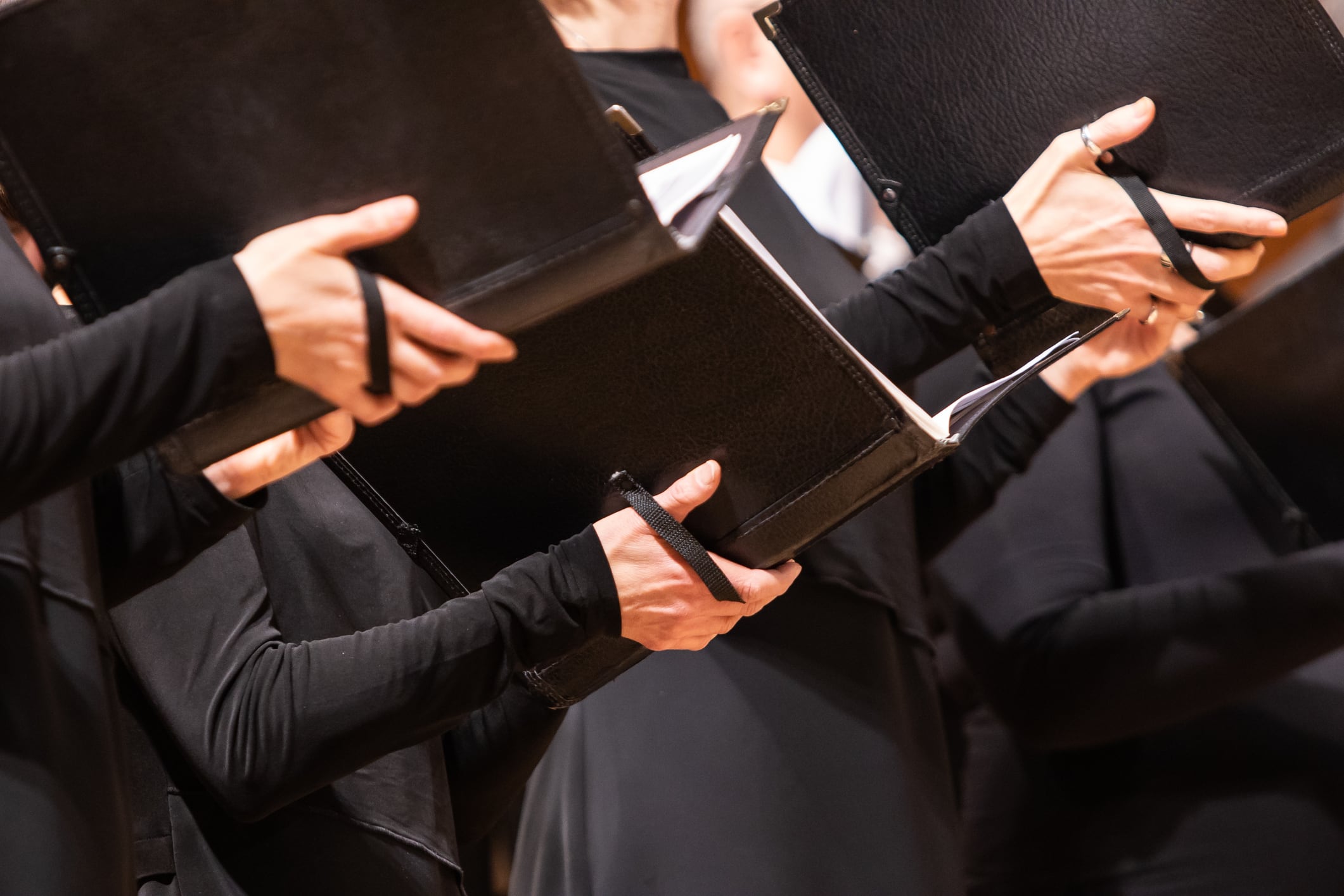 Hands holding sheet music in a choir, illustrating unamplified live music - one of the entertainment activities that can be performed without a premises licence under the Licensing Act 2003.