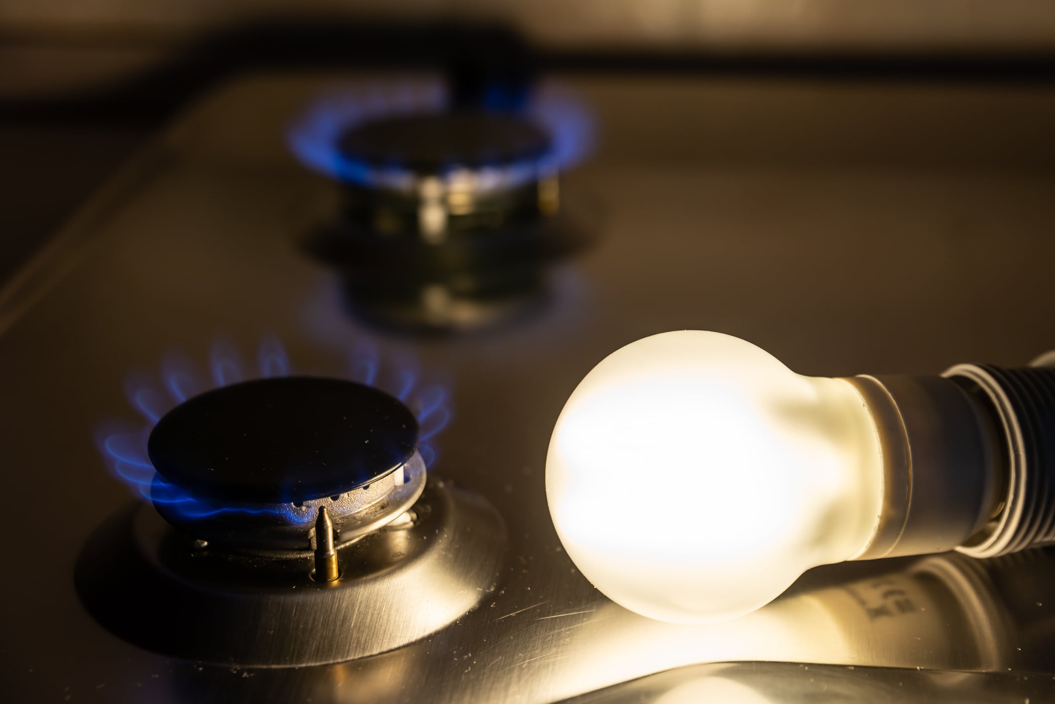 A lit lightbulb and a gas ring burning, symbolising rising electricity and gas costs facing pubs and hospitality businesses.
