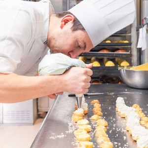 A pastry chef filling pastries with bag