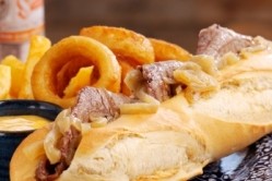 The Philly Cheesesteak Sandwich: Char-grilled, shaved rib eye steak, sautéed onion and Monterey Jack cheese, served in a baguette